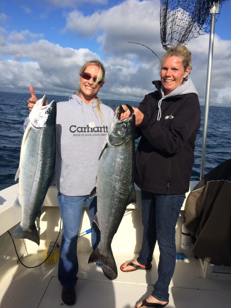 Two women holding Salmon and Steelhead fish Door County Wisconsin Reel Impression