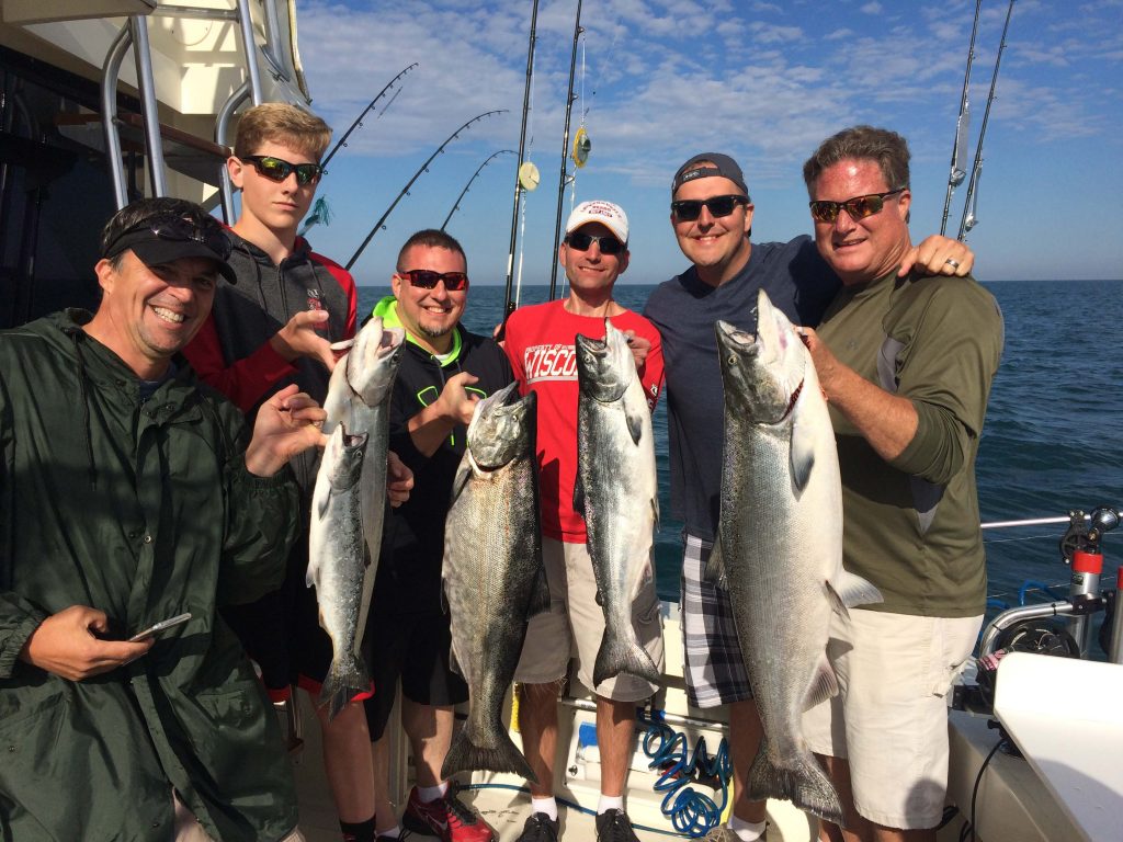 Group of men holding up Salmon and Steelhead, charter fishing in Door County Lake Michigan