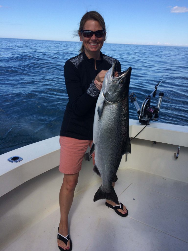 Woman holding up salmon on charter fishing trip Lake Michigan Door County Sturgeon Bay Wisconsin