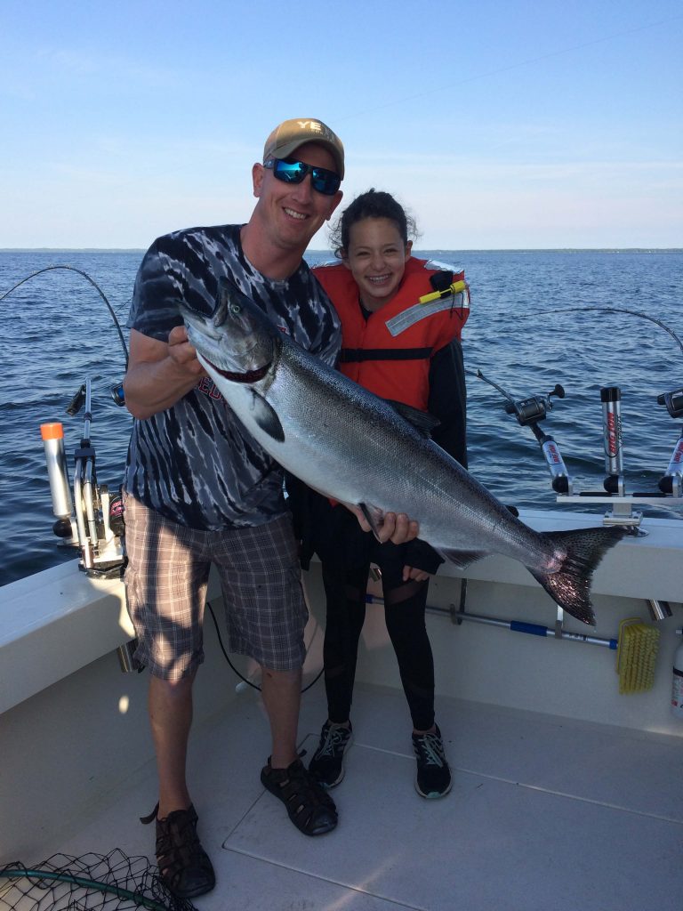 Man holding up large fish with little girl charter fishing in Door County Wisconsin