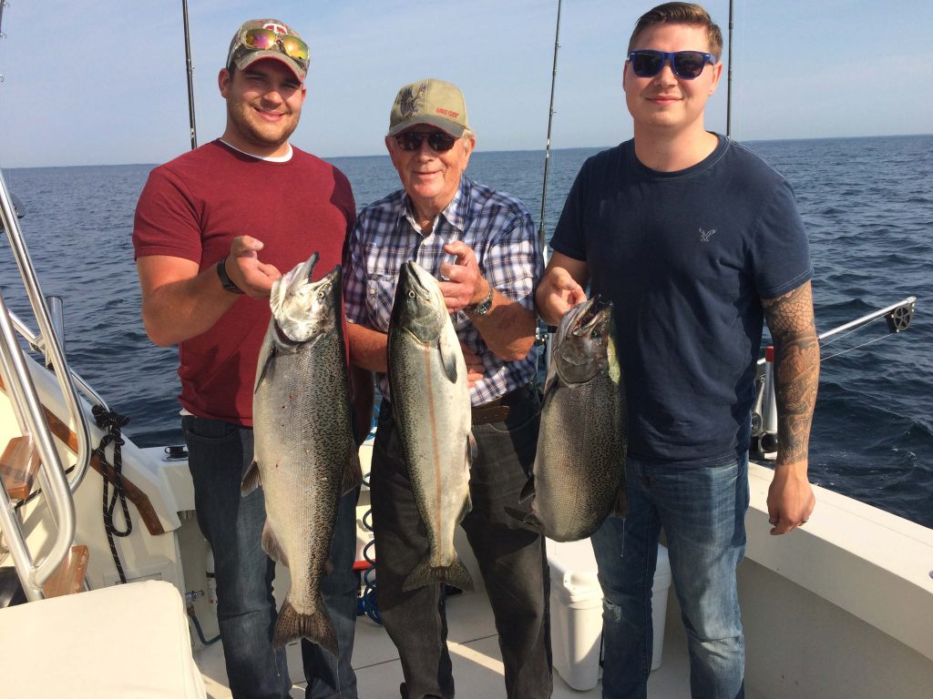 Three men holding up Lake Michigan Salmon
