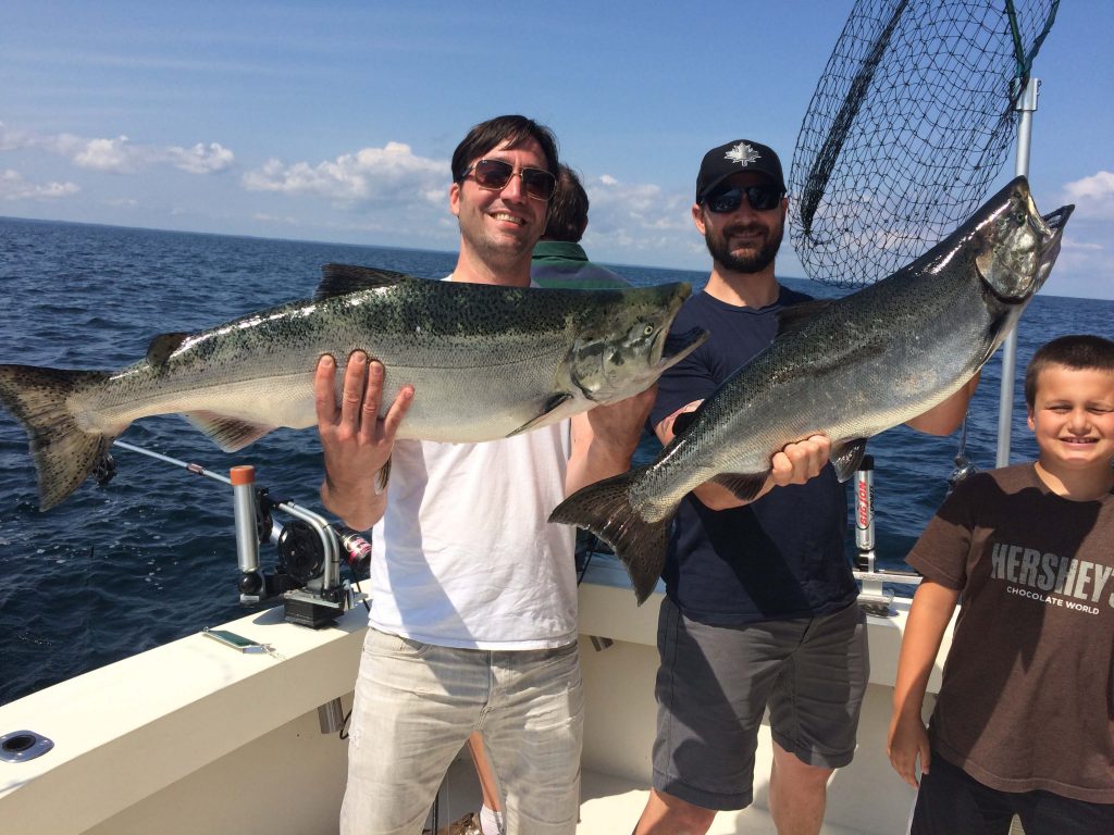 Two men holding up Lake Michigan Salmon