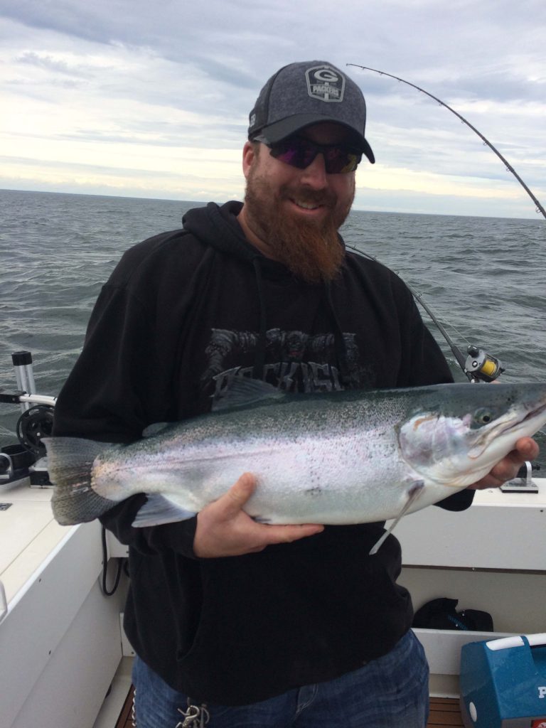 Man holding up Steelhead trout on charter fishing boat